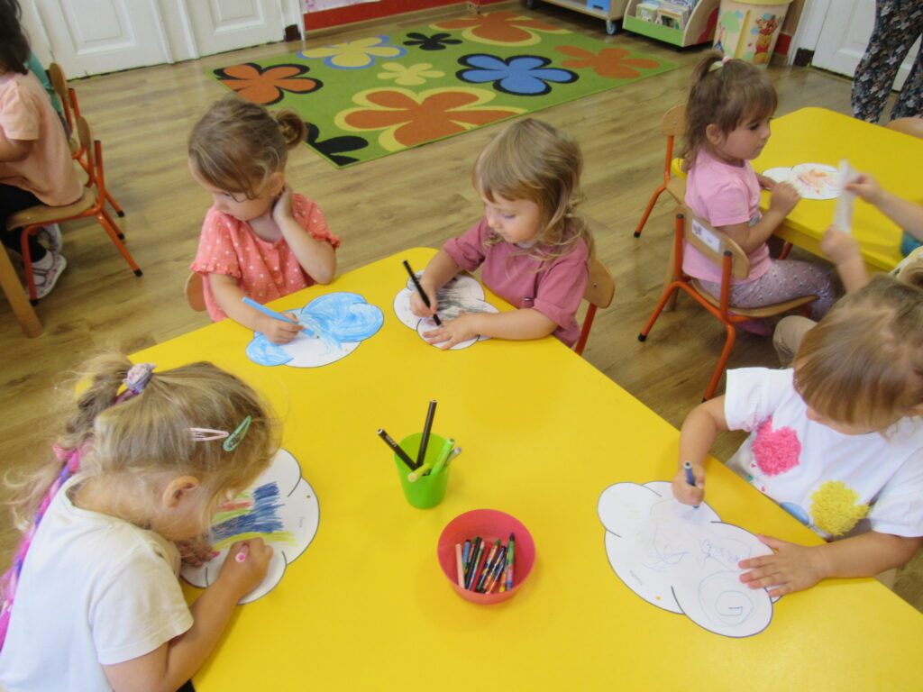 grupa dzieci rysuje przy stoliku