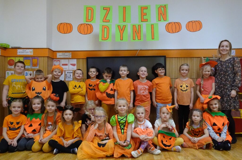 Zdjęcie grupowe, przedstawiające dzieci w ubraniach w kolorze pomarańczowym lub przebrane za dynie. 