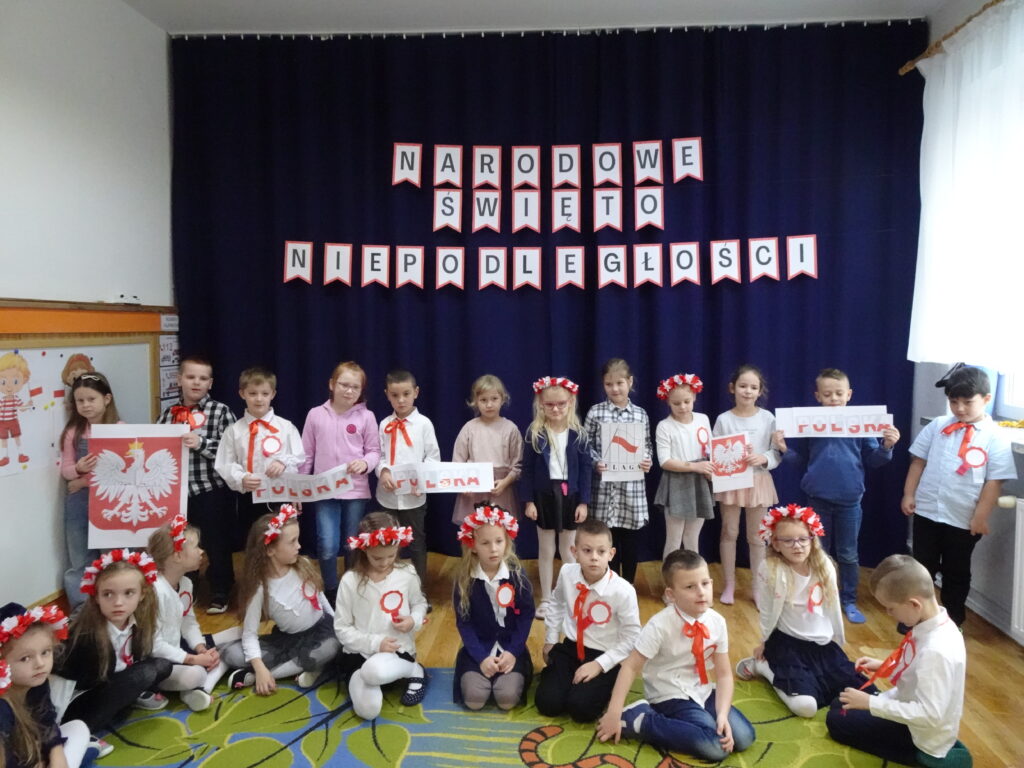 Zdjęcie grupowe. Niektóre dzieci trzymają symbole Polski.