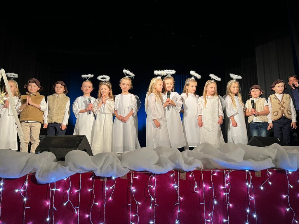 Zdjęcie grupowe na scenie Sławieńskiego Domu Kultury. Dziewczynki przebrane za anioły, chłopcy za pastuszków.