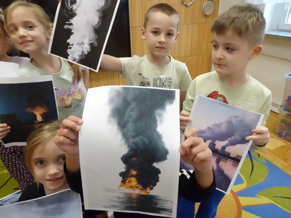 Dzieci ze zdjęciami przedstawiającymi różne dymy.