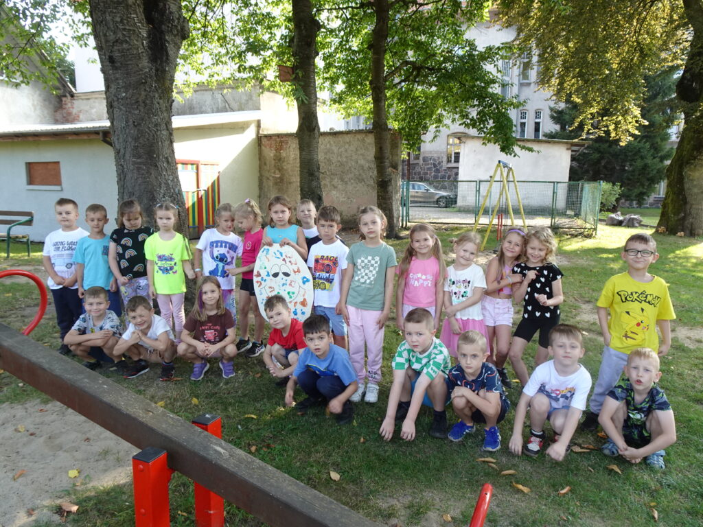 Zdjęcie grupowe w ogrodzie przedszkolnym. jedna dziewczynka trzyma w rączkach duży szablon ziemniaka.
