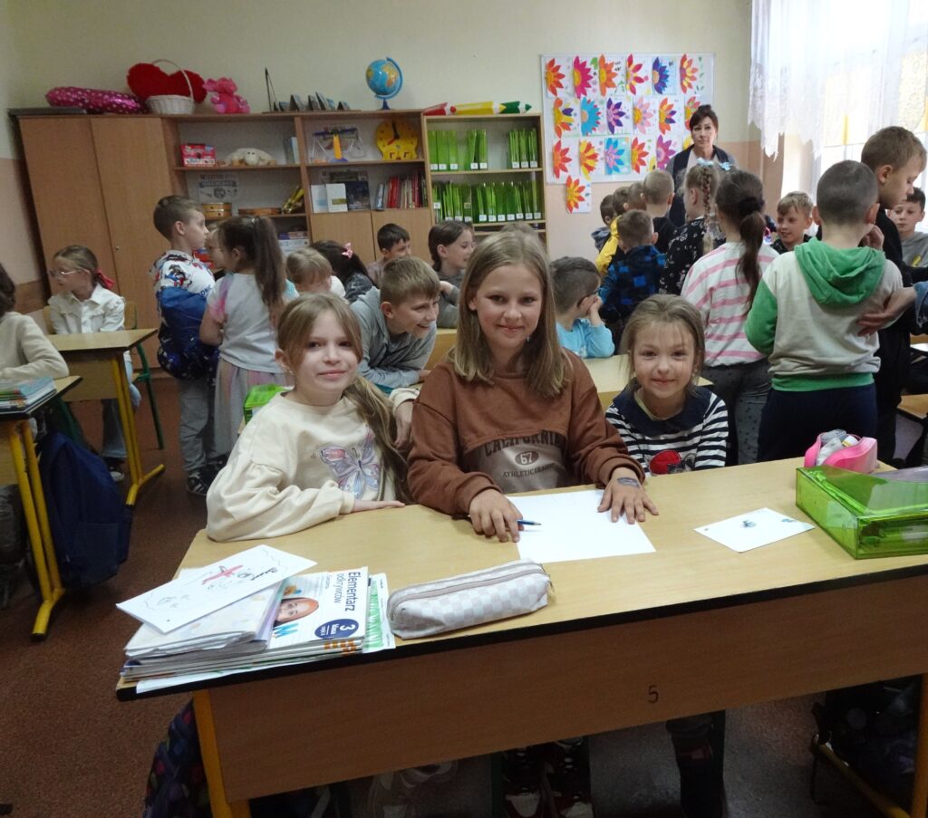 Dzieci siedzą w szkolnej ławce. 