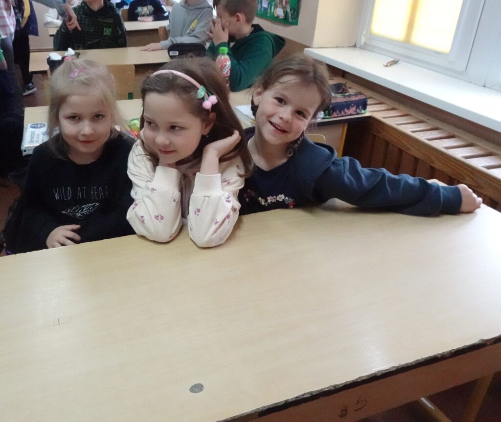 Dzieci siedzą w szkolnej ławce. 
