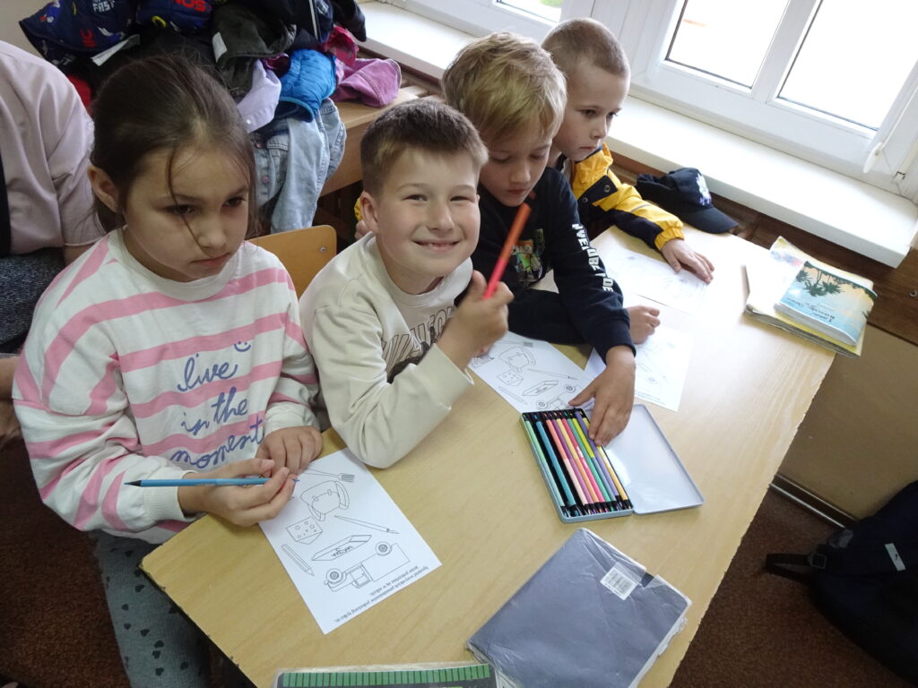 Dzieci siedzą w szkolnej ławce. 