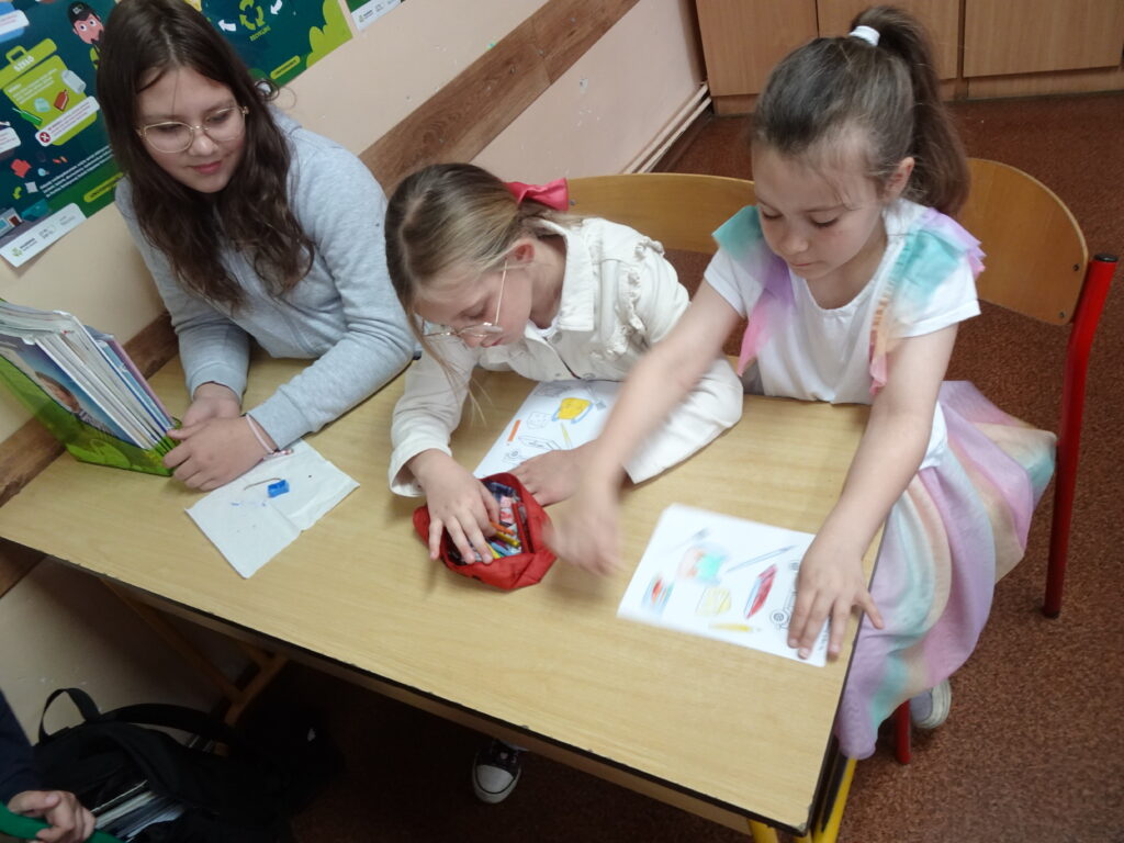 Dzieci siedzą w szkolnej ławce. 