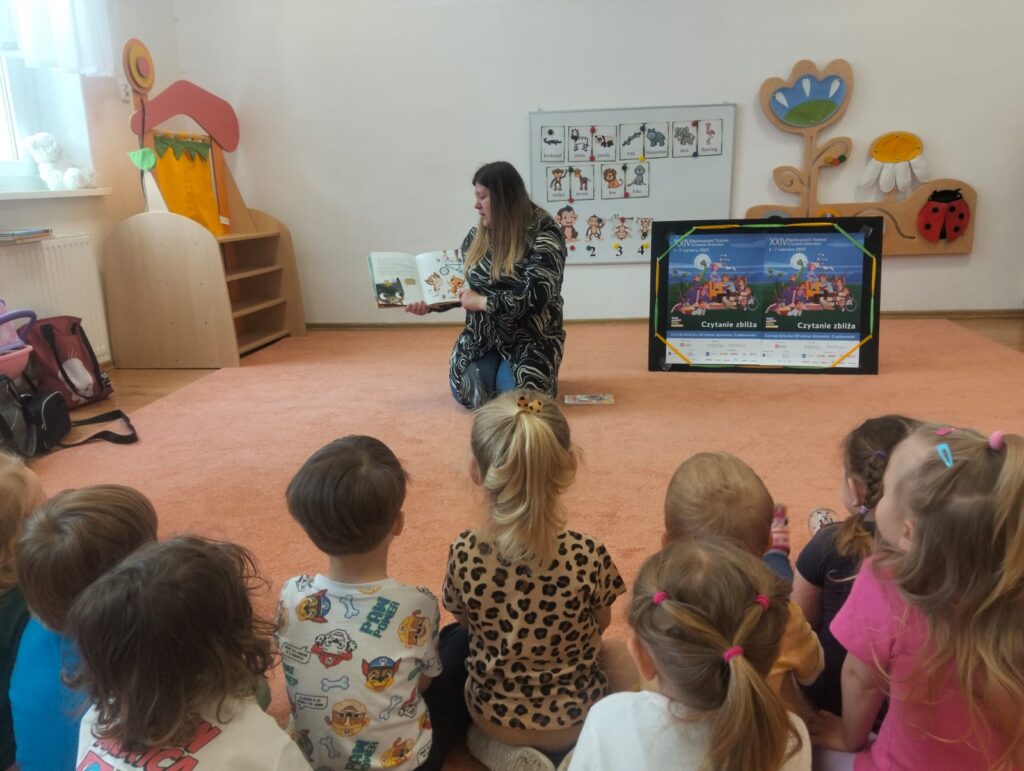 Dzieci podczas słuchania bajki, czytanej przez panią z biblioteki. 