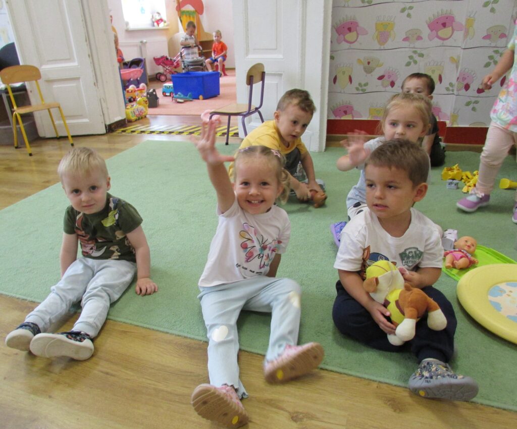 Dzieci siedzą na dywanie. 