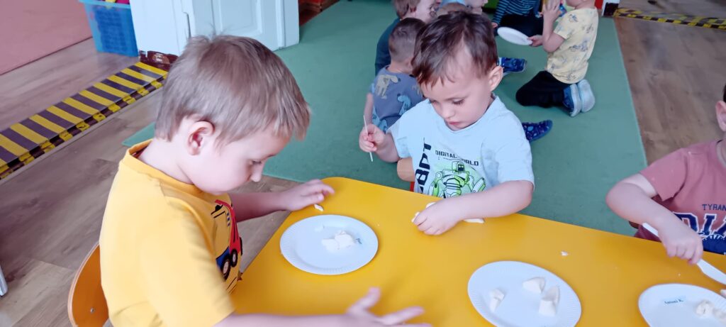 Dzieci przy stoliku podczas zabawy masą solną.