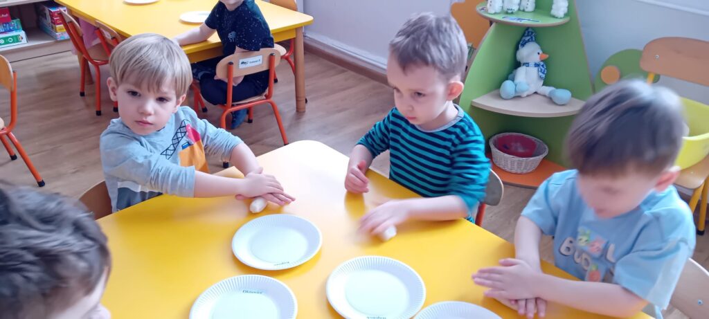 Dzieci przy stoliku podczas zabawy masą solną.