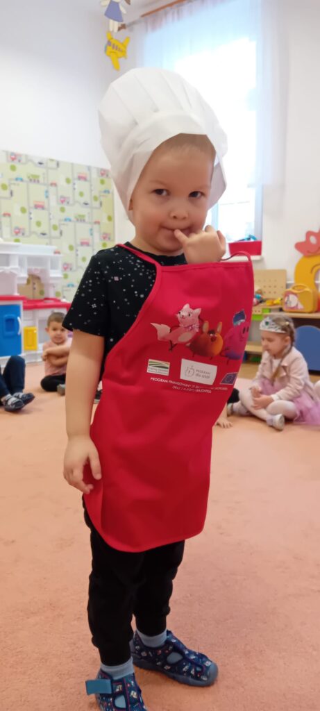 Chłopiec w fartuszku i czapce kucharskiej.